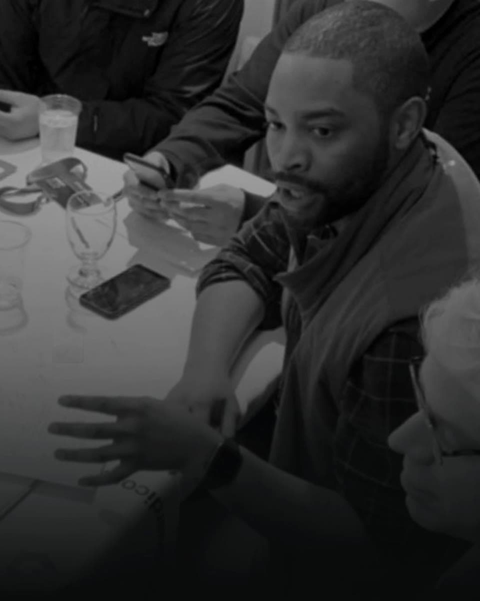 A working session in Tel Aviv: Micah mid-discussion at a table of notes, phones and glasses.